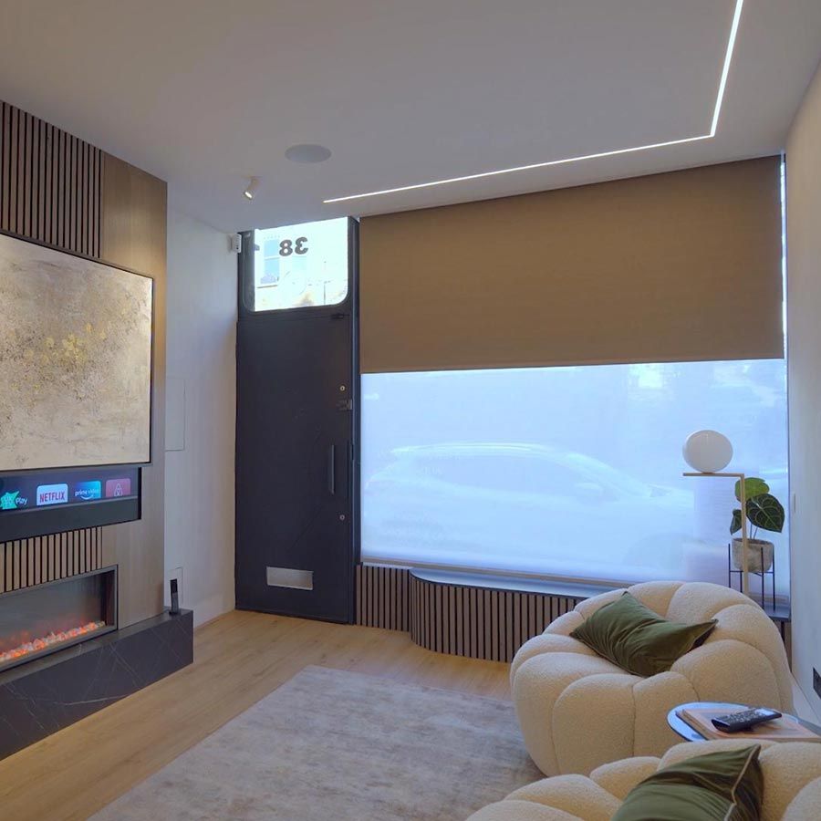 Motorised shades lowering over large windows in a bright beachfront living room