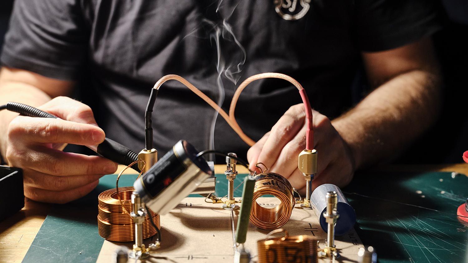 Hands assembling speaker crossover components with copper coils