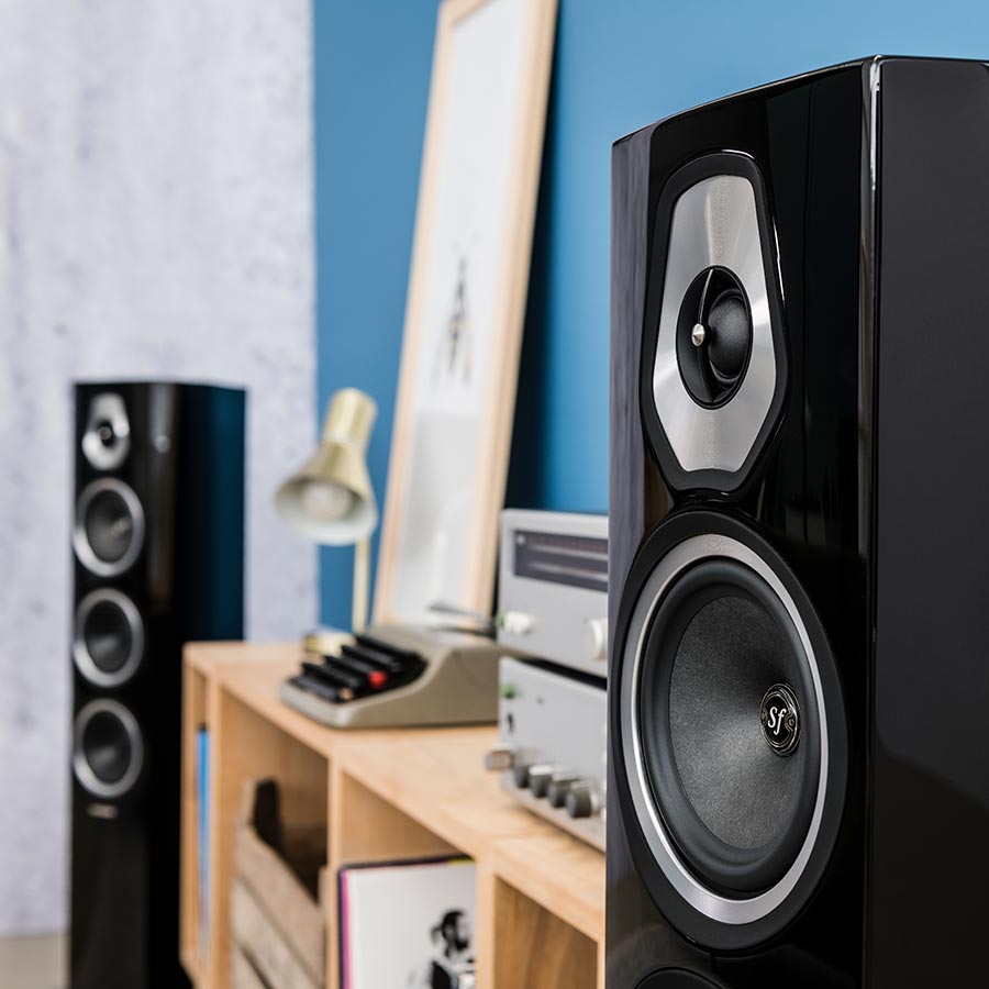 Gloss black floorstanding speakers placed in a modern listening setup