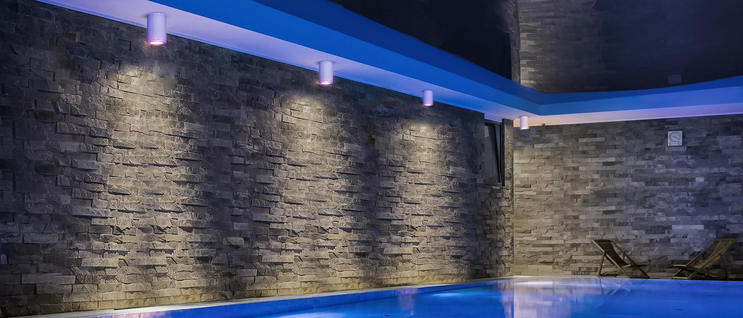 Poolside lighting casting dramatic shadows on a textured stone wall