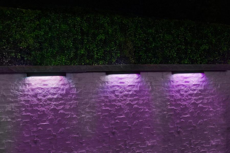 Purple-toned wall wash lighting illuminating a textured stone wall