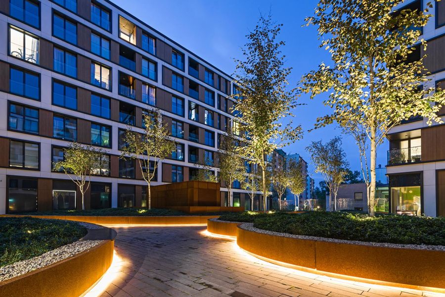 Curved courtyard in front of urban apartments highlighted with trim lighting
