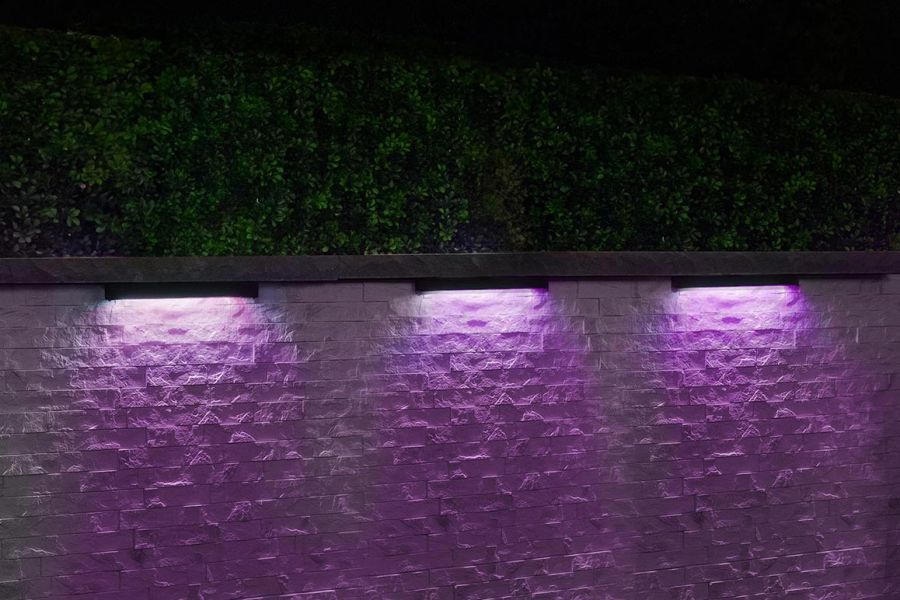 Purple-toned wall wash lighting illuminating a textured stone wall