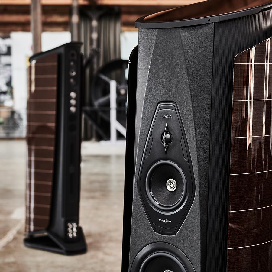 Close view of floorstanding speakers with dark wood sides in an industrial interior