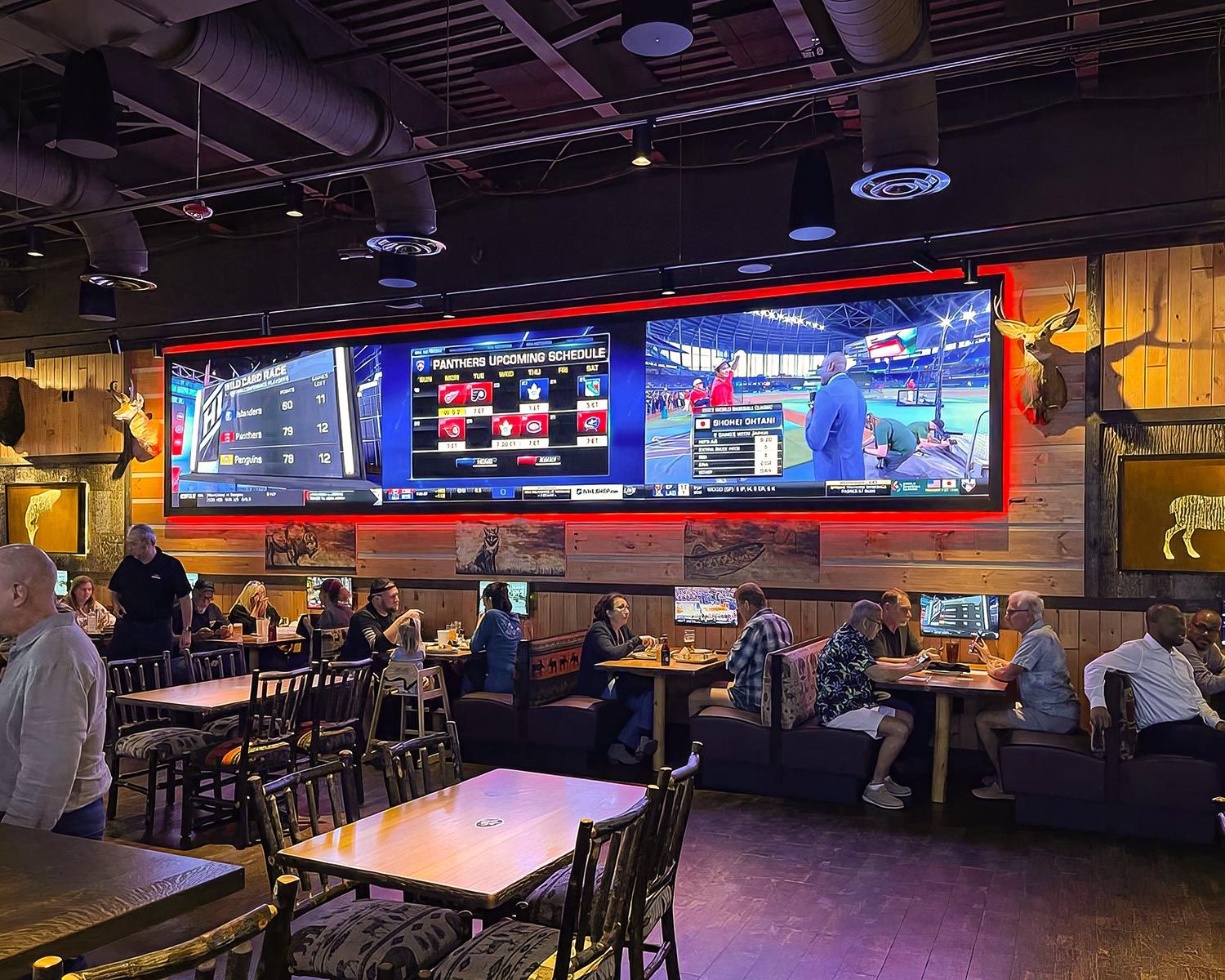 Busy sports bar with multiple MicroLED screens showing live games and scores